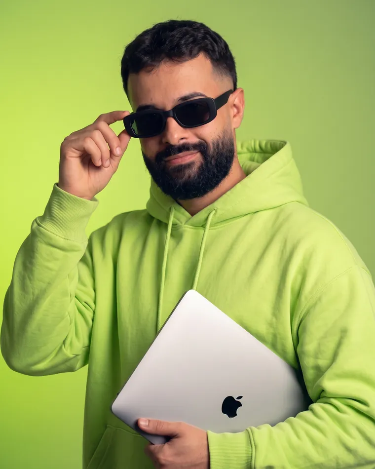 Israel Meira de moletom lime, com um MacBook debaixo do braço, ajeitando os óculos escuros
