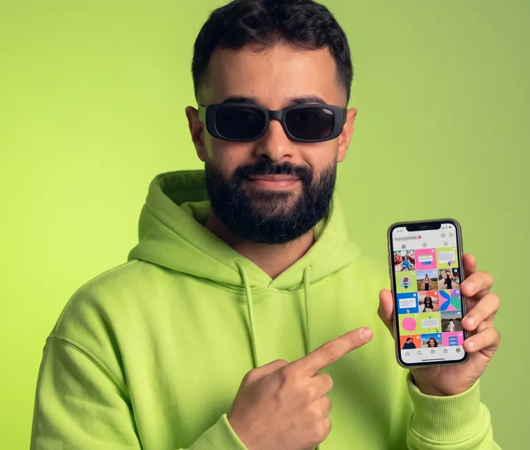 Israel Meira de moletom lime, apontando para o celular com um feed de posts na tela